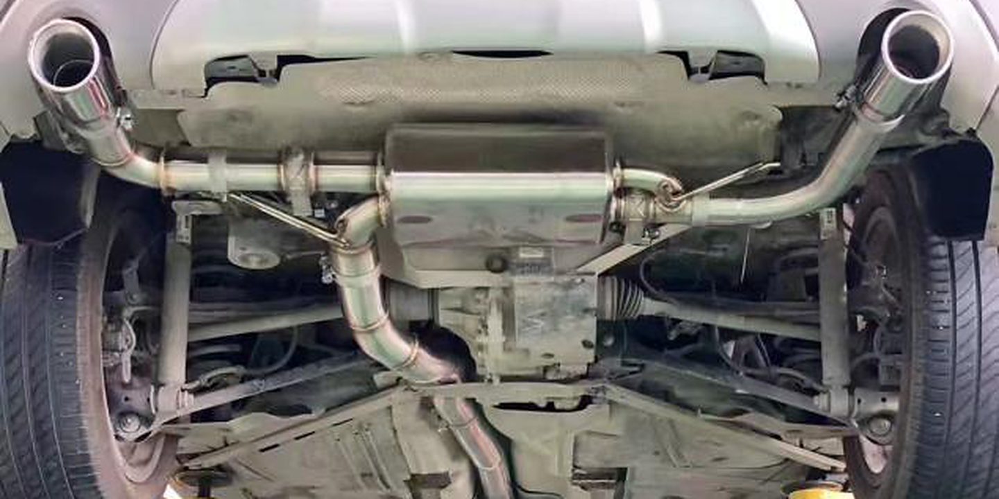 Cat-back system fitted under a car on a lift, seen from behind
